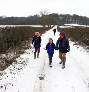 Four kids holding hands walking in snow